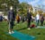 Students practice yoga on a sunny day on a grassy area.