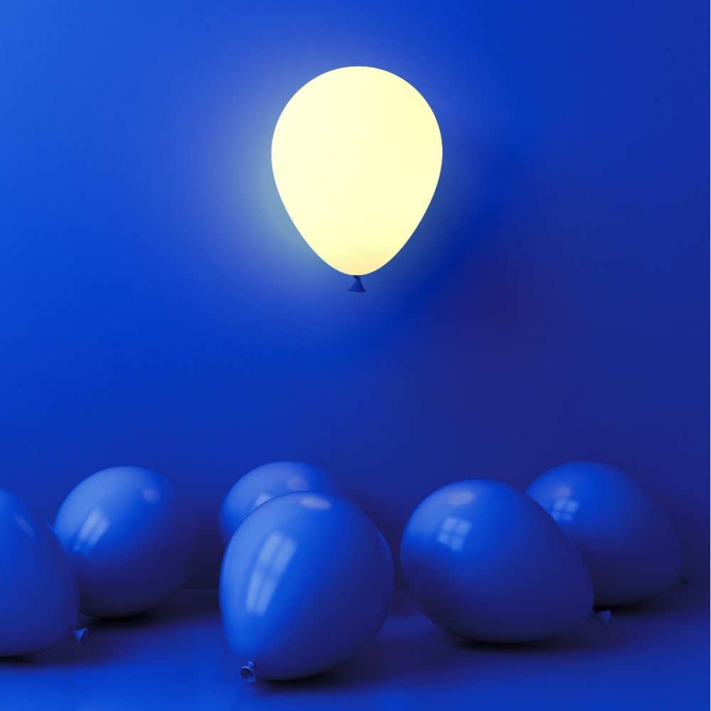 A white glowing balloon floats in a electric blue room with blue balloons lying on the floor.