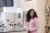 Kizzmekia Corbett in a pink long sleeved dress, laughing at the camera in a science lab. Her hair is dark. long and wavy.