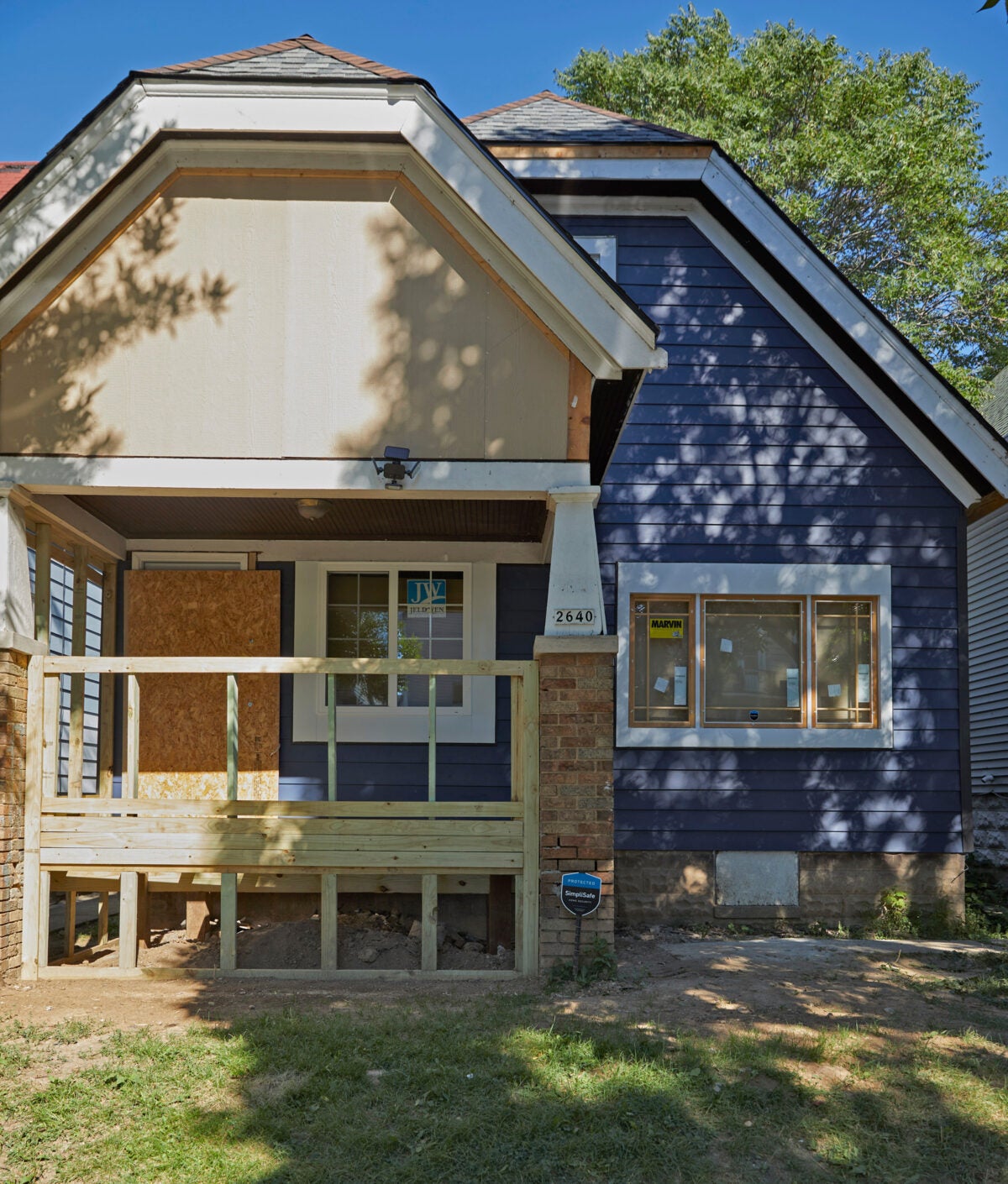 A house with blue siding with the framing of a porch in 2x4s.