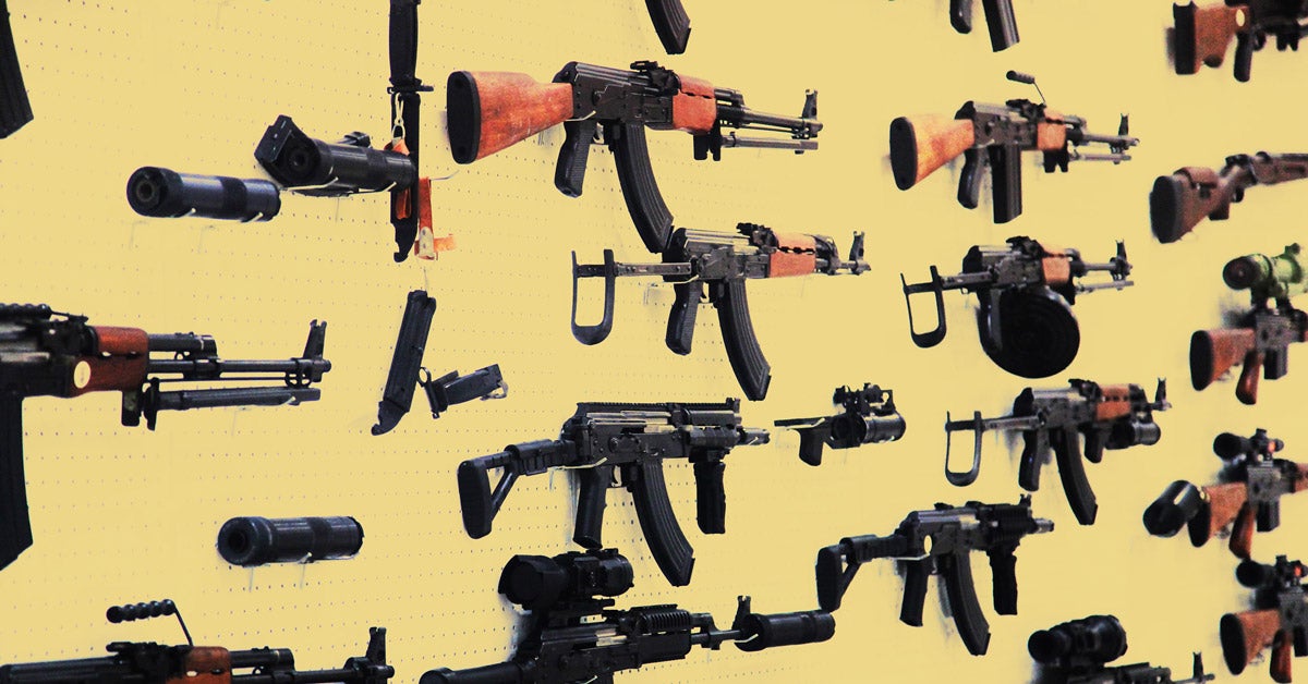 Assault rifles hang on a yellow pegboard.