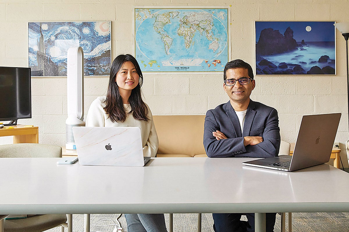 Jie Sun (left) and Amber Nigam  (right) sit at a table in a student workroom at the Harvard Chan School of Public Health.
