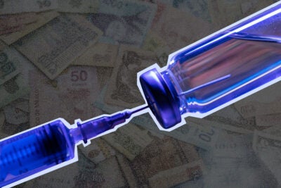 Photo illustration: A blue vaccine vial and syringe are overlaid on a grey-speckled background of paper currency from different countries.