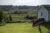 A Black woman walks in her large mowed grass lawn in rural North Carolina. Other houses in a far off subdivision are visible in the background.