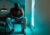 Byron Stribling sits on a chair and looks out a window inside a waiting room. The photo has a teal tone.