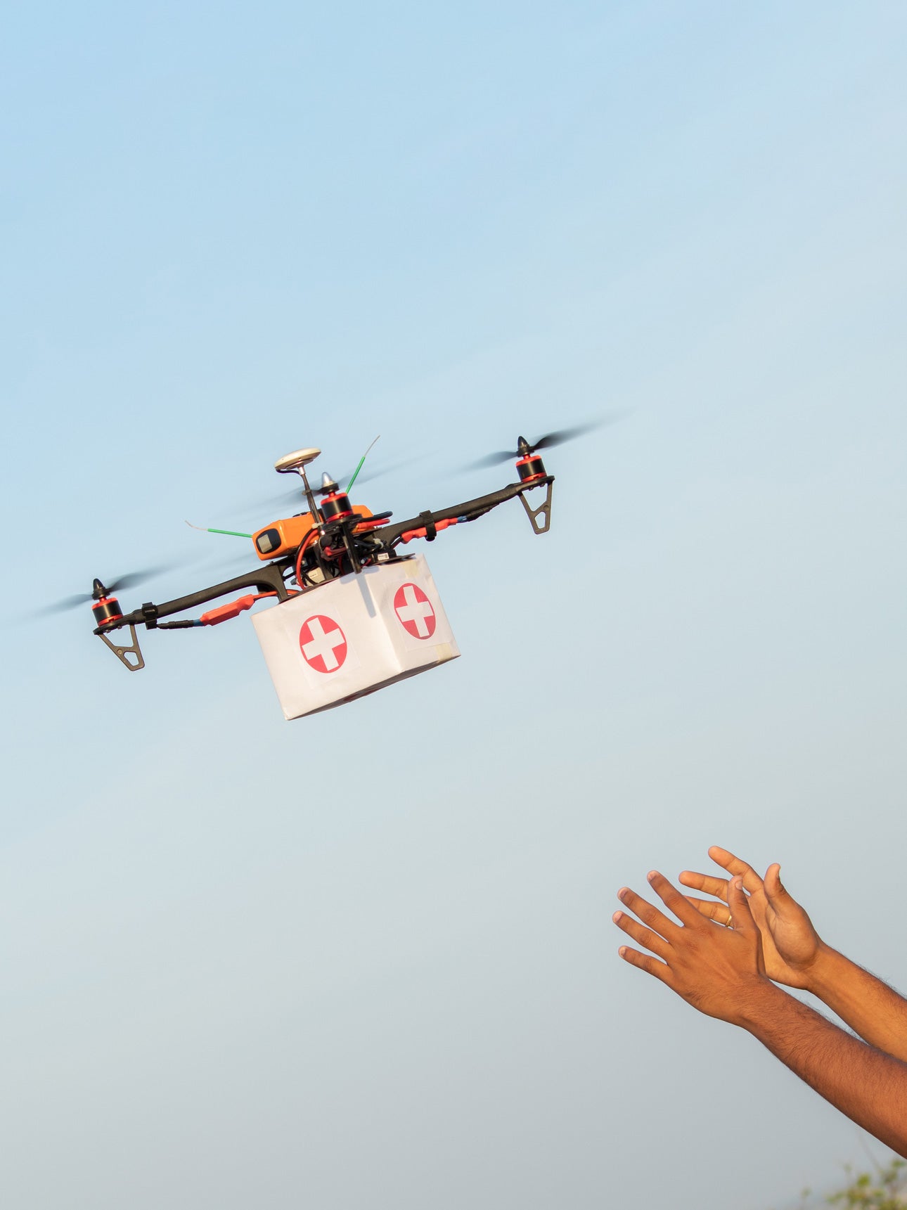 Drone carries first aid box to a pair of outstretched hands.