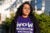 Yuli Paez-Naranjo stands with a purple "WOW Youth Guidance" tshirt, black cardigan, and clear glasses and looks directly at the camera. She is photographed in front of a while building with green shrubs.