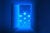 Digital illustration: A door in dark room opens to reveal floating health and data icons. The composition is shades of blue.