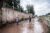 Two men walk barefoot on a muddy, flooded road in Bangui.