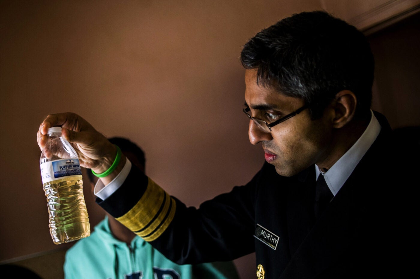 U.S. Surgeon General Vivek Murthy inspects a plastic bottle filled with murky tap water in a Flint, Michigan home.