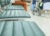 一名男子坐在候诊室的一排座位上，护士和轮椅穿过医院繁忙的走廊。