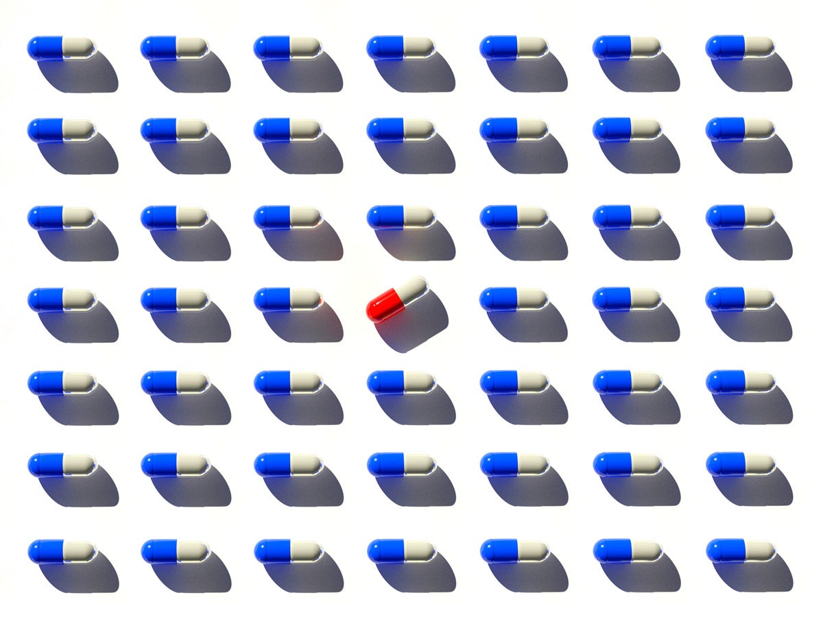 Organized rows of white and blue pill capsules. A white and red pill is in the center and turned 45 degrees.