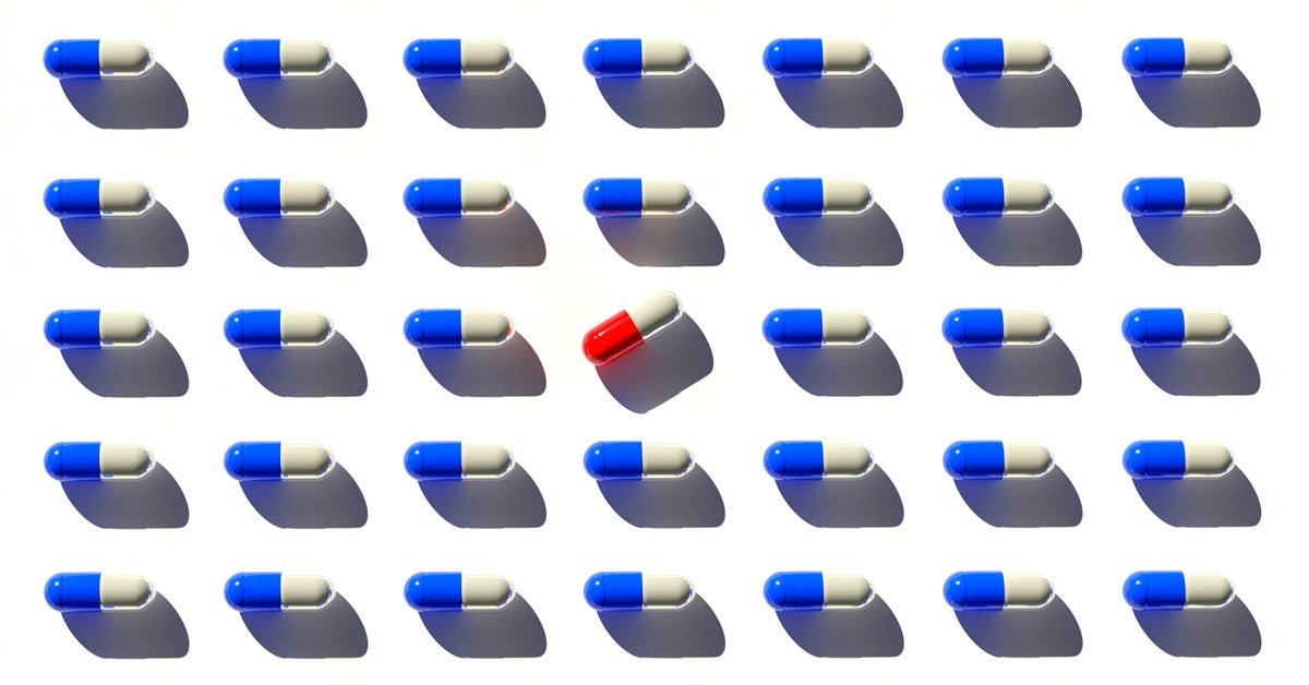Organized rows of white and blue pill capsules. A white and red pill is in the center and turned 45 degrees.