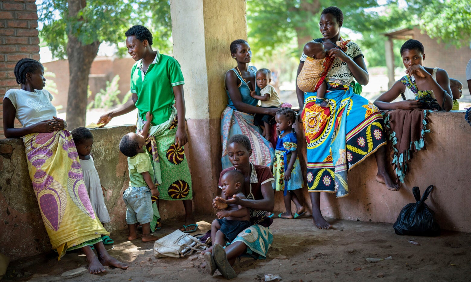 A group of African women and their children wait on a balcony.