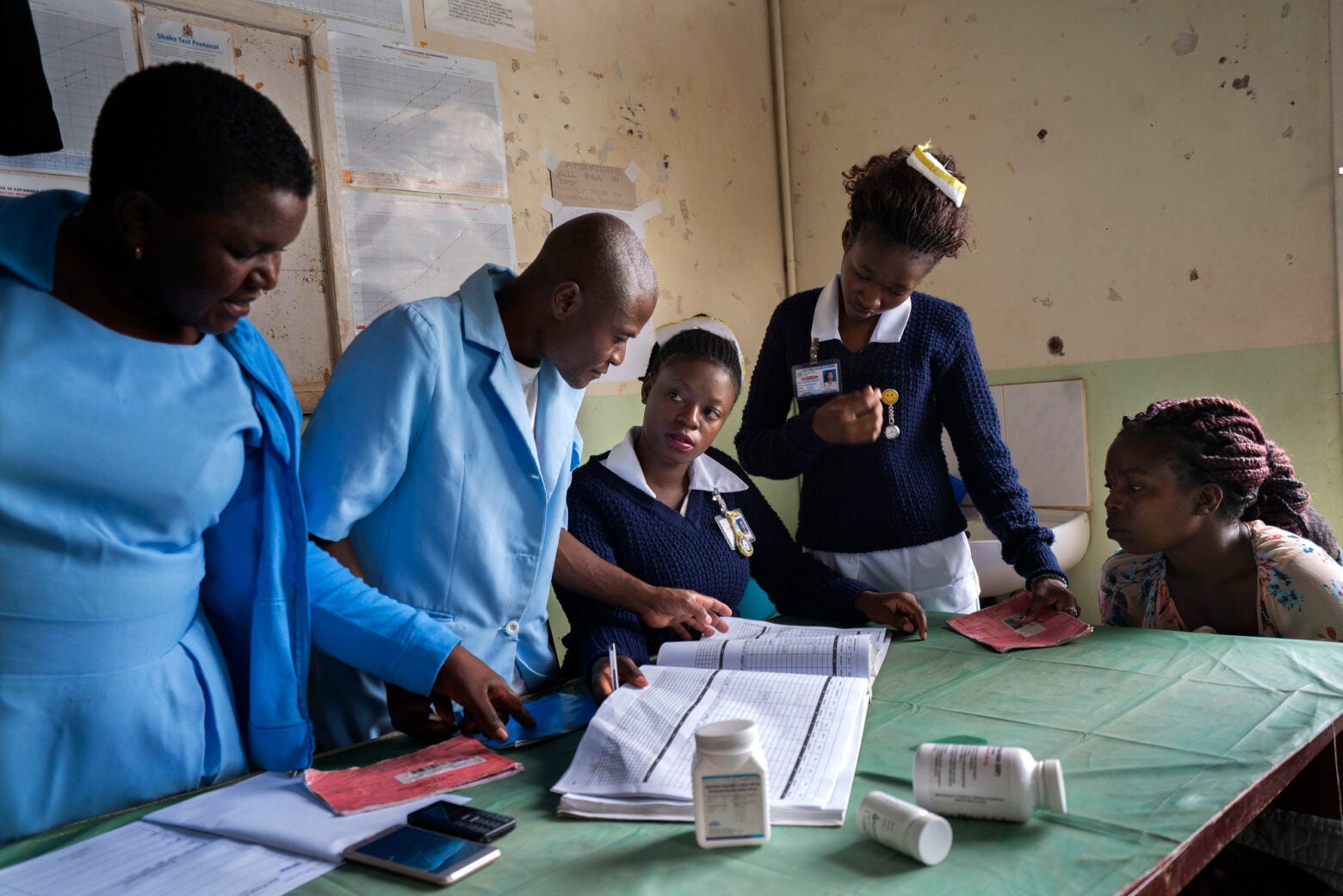 A group of African health workers look at a document laid out in front of them.