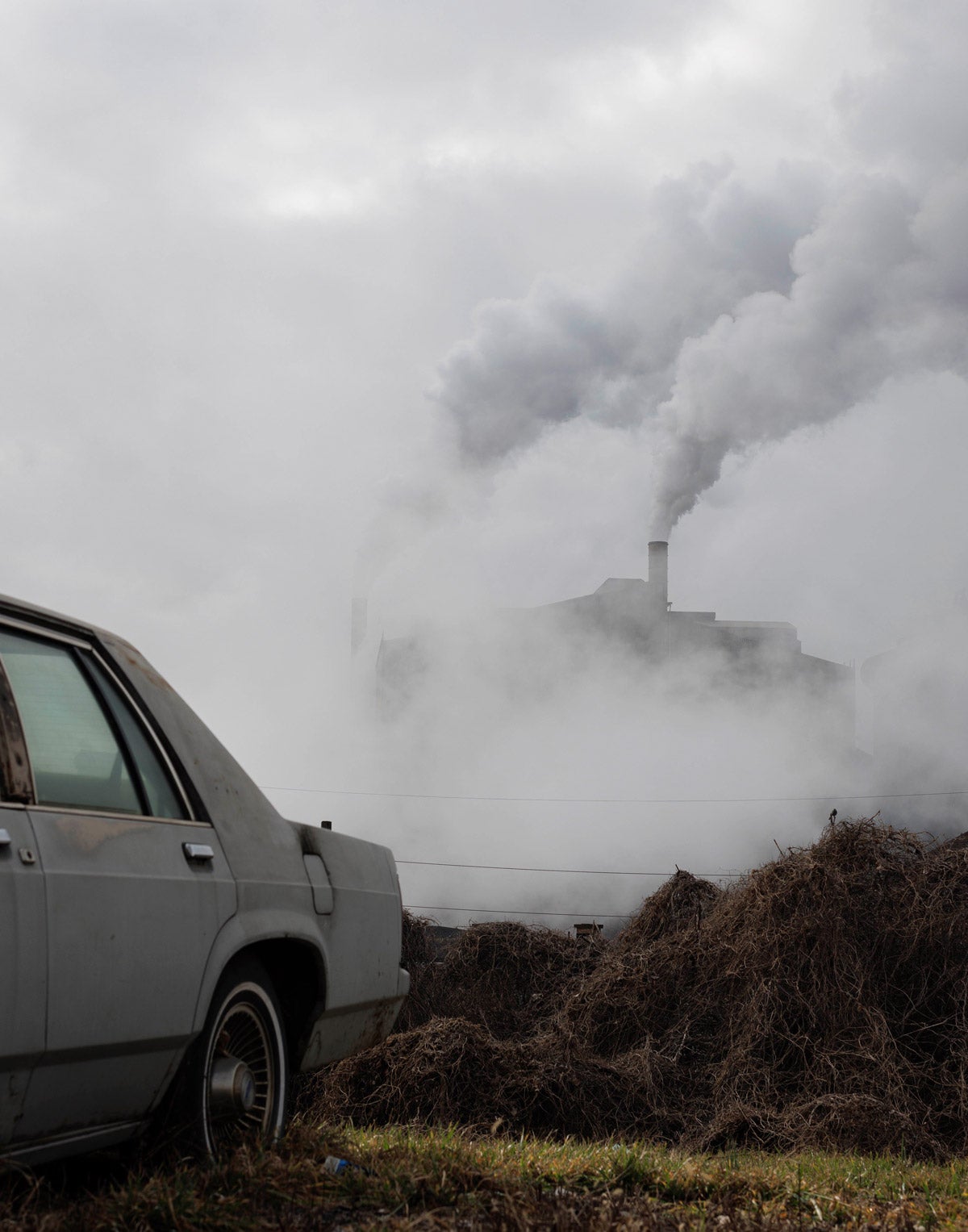 Smoke emissions from a steel plant in rural Pennsylvania. An old car is in the foreground, nearly out of frame.