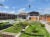 A steel, white and wood series of buildings and green plots of grass and plants, part of the ACEGID campus in Ede, Nigeria.