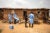 A team of three medical researchers put on PPE in a dirt village in Isuda, Nigera. A single-story, mud house is behind them.