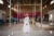 Alaba Aladesanw, wearing all white, stands in the middle of her church's white tile floor and stares directly at the camera.