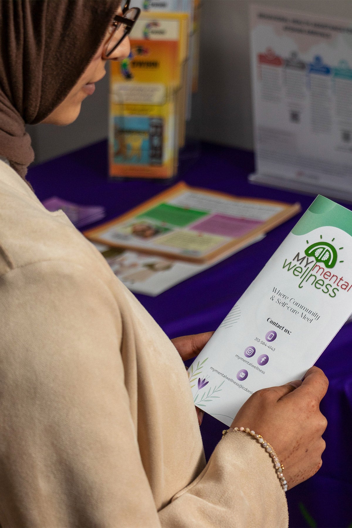 A woman wearing a hijab reads a pamphlet on the My Mental Wellness clinic.