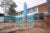 Kibera Primary School's dirt school yard. To the right, a large black water drum is connected to blue wires and a blue pillar stands to its left.