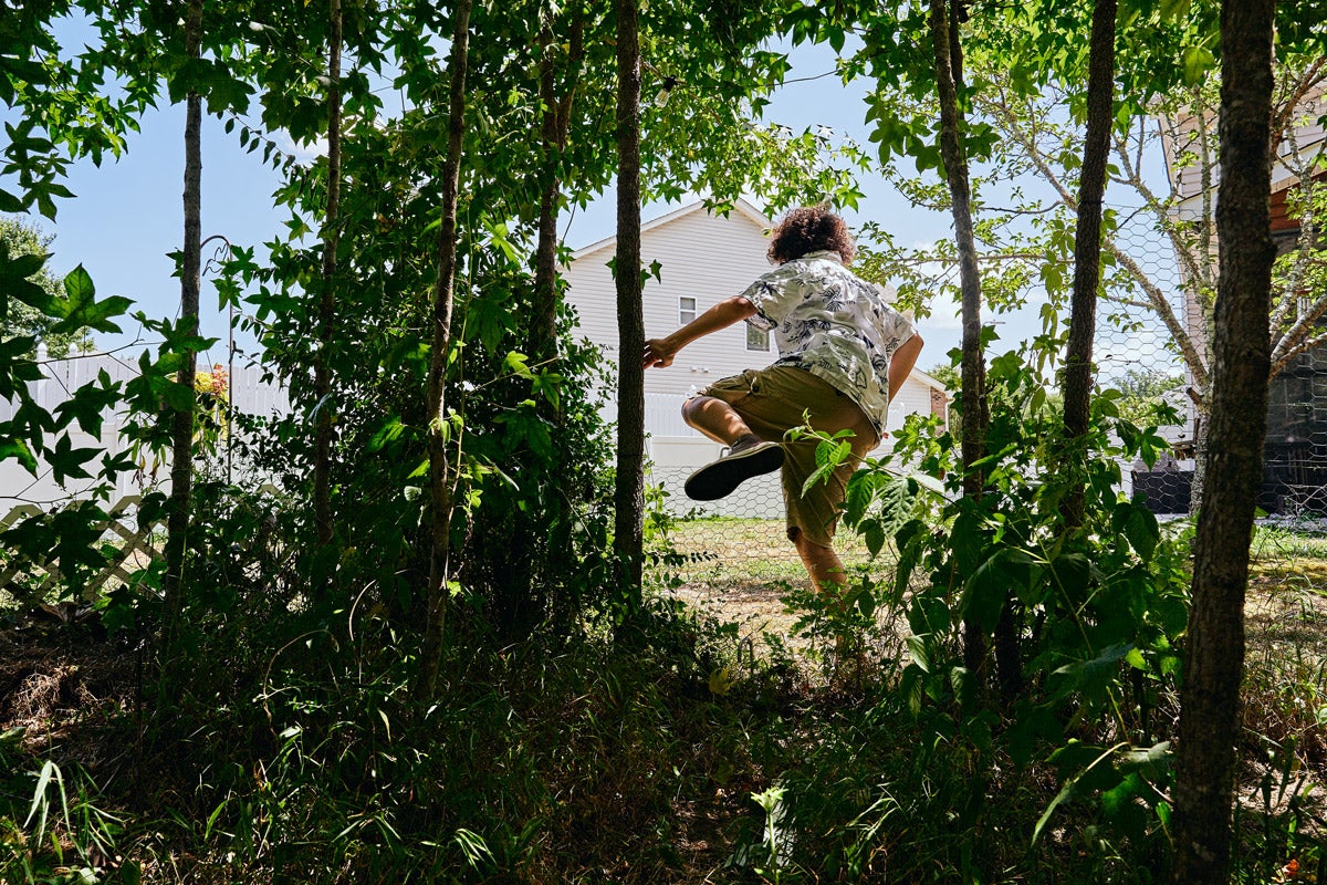 A young teen climbs over a chicken wire fence in suburban North Carolina.