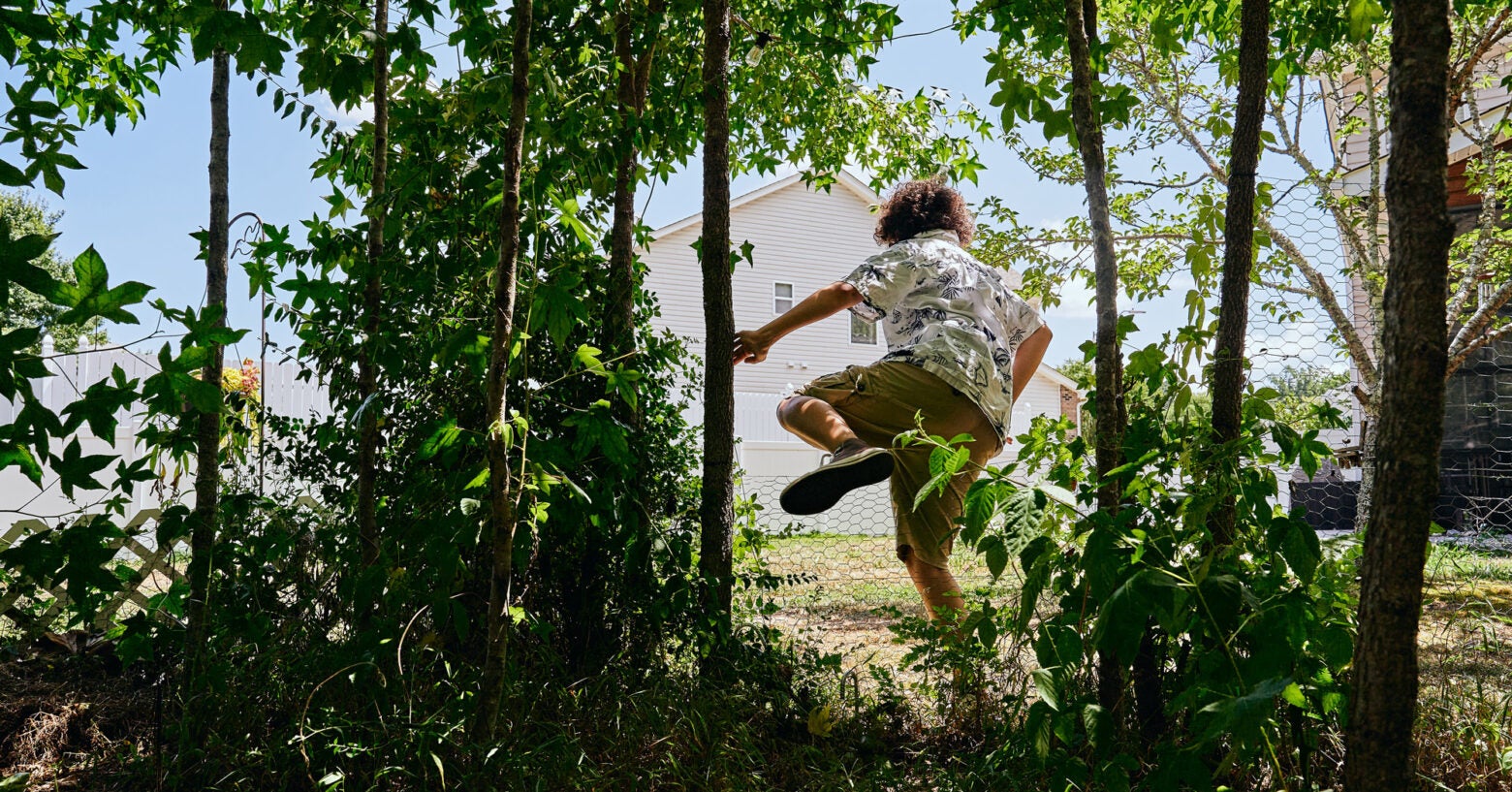 A young teen climbs over a chicken wire fence in suburban North Carolina.