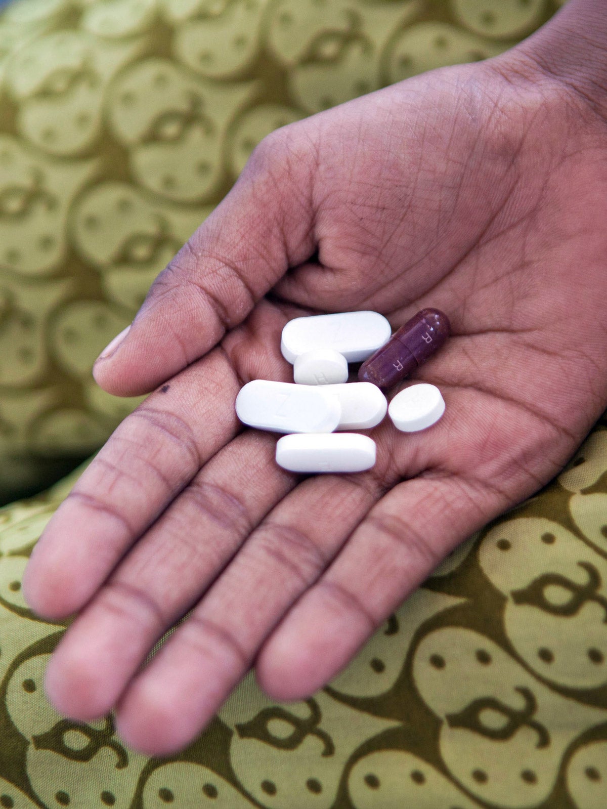 A hand holds seven tuberculosis (TB) medication pills at a health care clinic in Delhi, India.