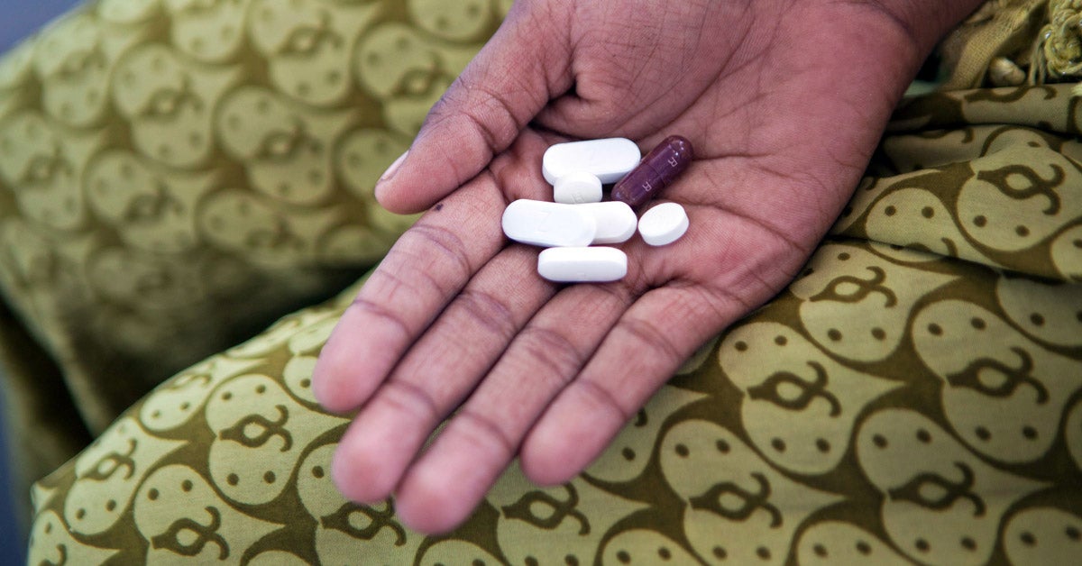 A hand holds seven Tuberculosis (TB) medication pills at a health care clinic in Delhi, India.