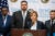 Jennifer Layden speaks into two microphones at podium at a city of Chicago press conference. Three other officials stand behind her.