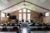 A parish hall set with long tables, chairs, white tablecloths and flowers. The three windows in the center have the words: hope, faith, love.