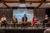 Five panelists sit on a stage in conversation. Behind them is a screen that reads "Making AI a Lifesaver: A Hopkins-Harvard event in D.C."