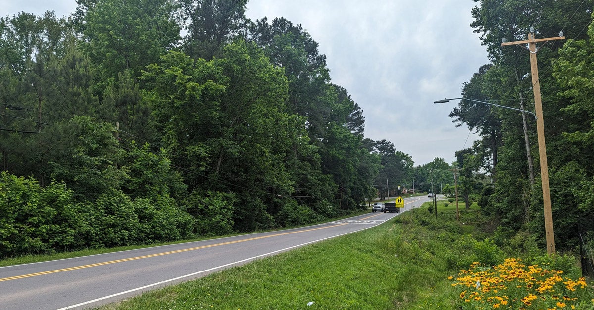 A two-lane highway on a wooded road outside Durham, North Carolina. The road has no sidewalks.