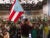 Politician Juan Dalmau, photographed from behind, waves a Puerto Rico flag in front of a large crowd of supporters at a convention.