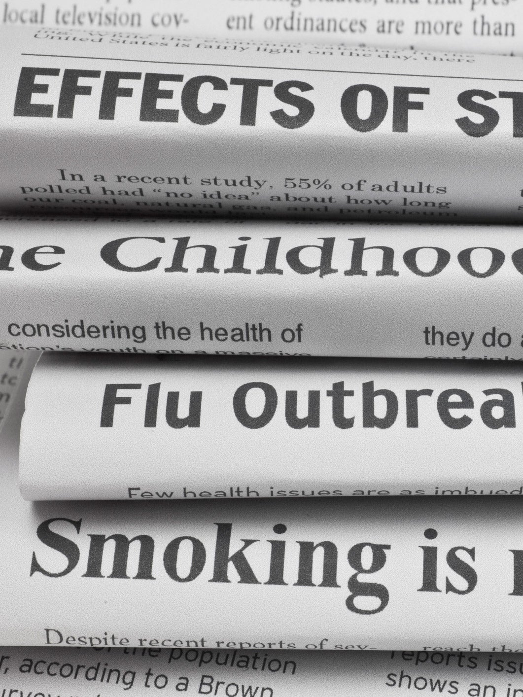 A stack of newspapers with health care headlines: “Effects of stress on you…” “The Childhood Obesity…” “Flu Outbreak...” “Smoking is riskier than…”