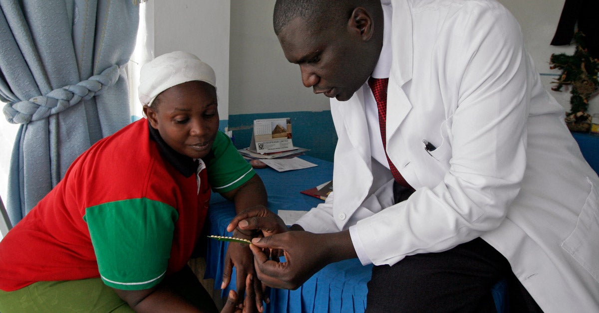 A male Kenyan doctor show a birth control packet to a female patient at a clinic in Nairobi.