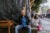 Arturo Ortiz sits on a concrete bench on a Mexico City street. Behind him is a structured covered in a black tarp. To his right are three young girls with rollerblades, sitting and eating.