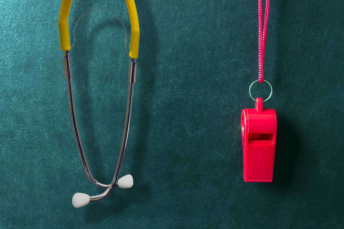 A red whistle and yellow stethoscope hang in front of a teal textured background.