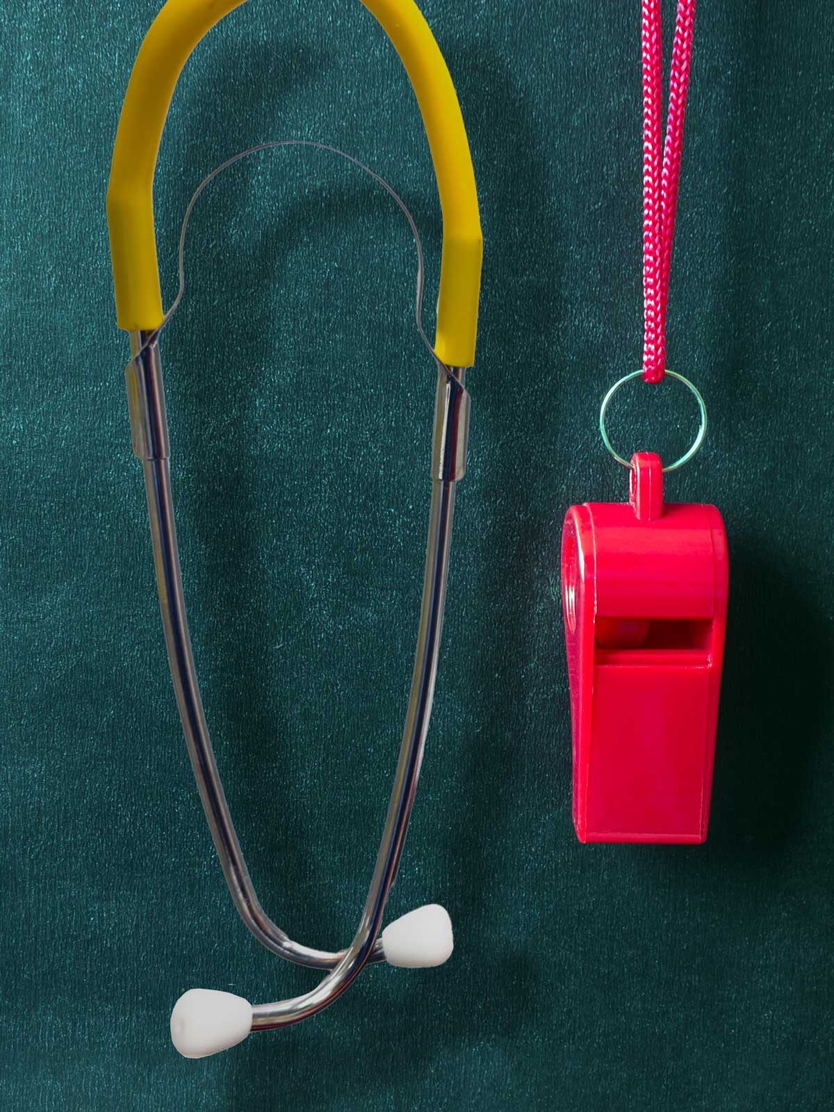 A red whistle and yellow stethoscope hang in front of a teal textured background.