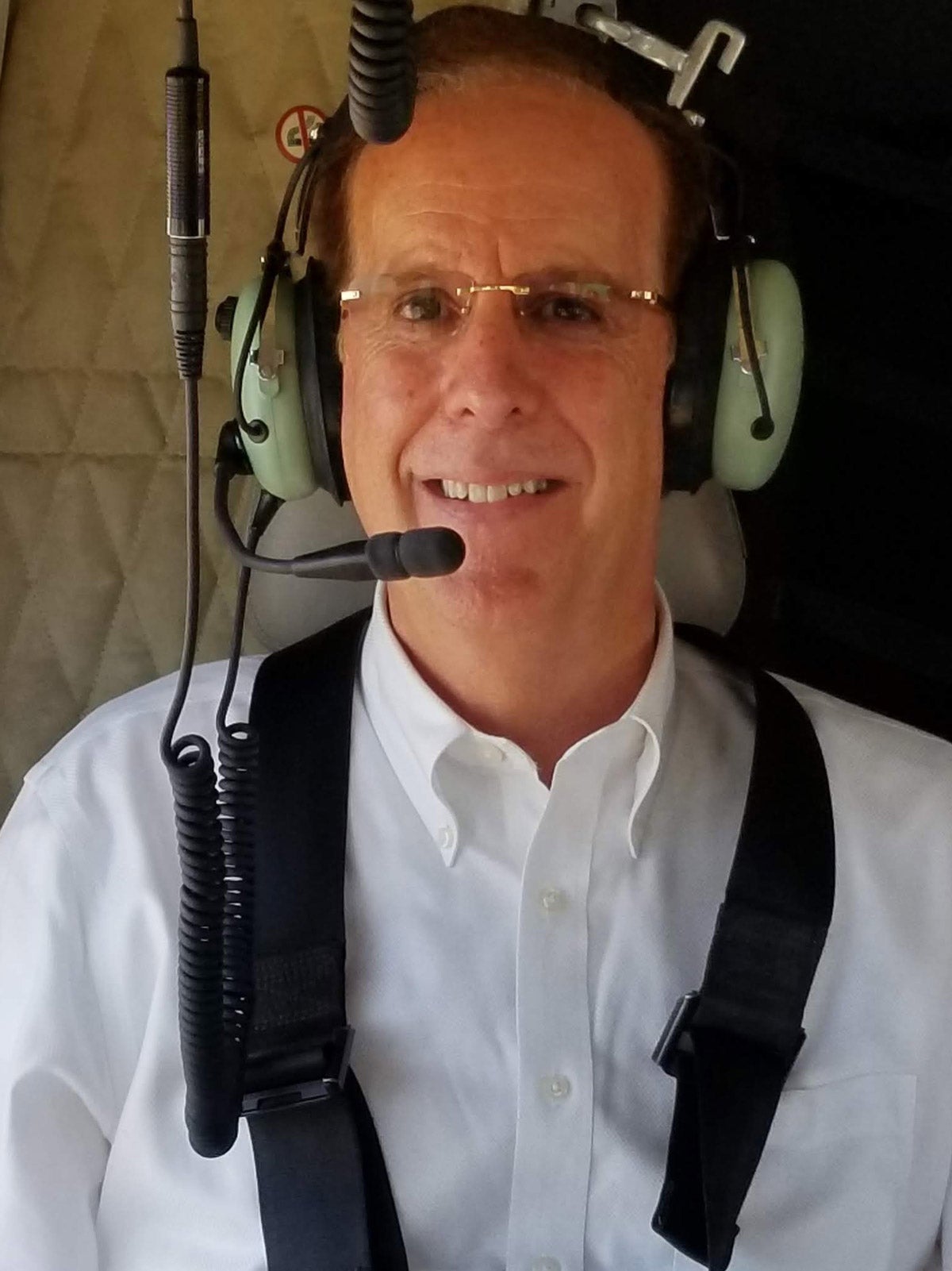 Brent Woodworth in a helicopter. He wears a light green headset.