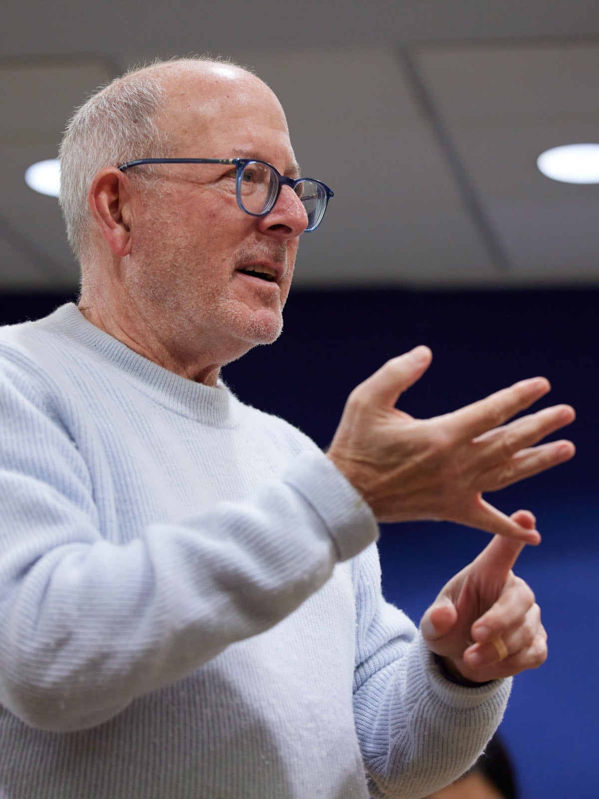 Andy Burness counts on his fingers while speaking to a class