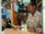 Moses Muthom, a Kenya herbalist, looks at a bottle of medicine in his hand while standing behind counter.