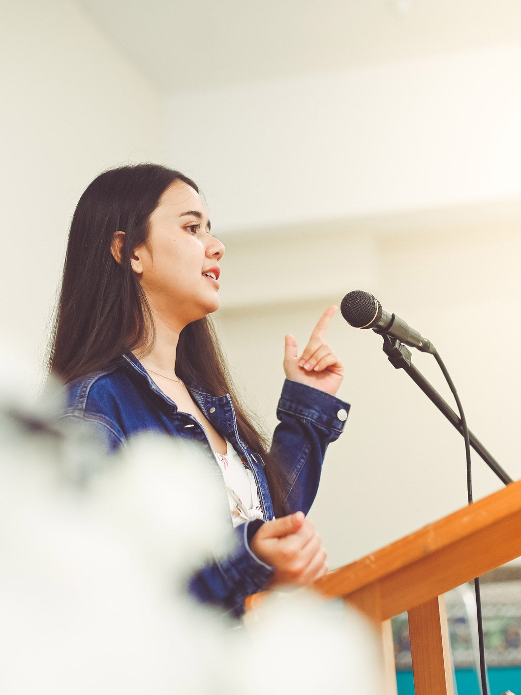 A young woman speaks into a microphone at a podium