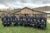 Members of the Los Angeles Community Brigade Program in matching hats and jackest, pose for a photo outside a wooden building in rural California.